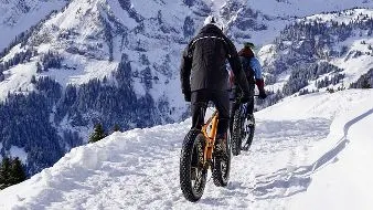 two guys riding a bicycle in the snow