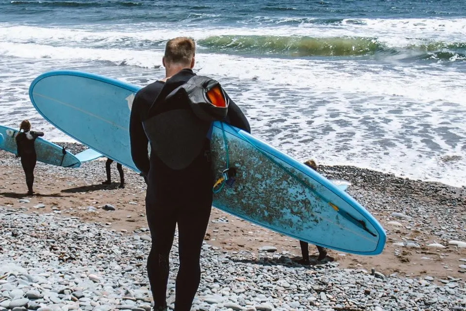 four foreiners getting ready to surf on the sea