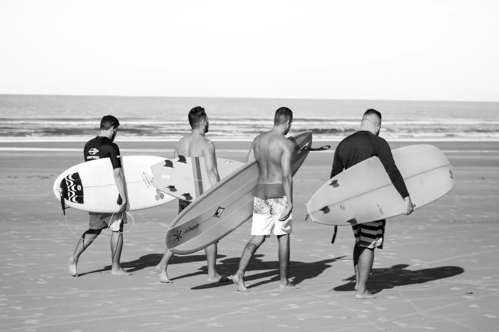 four men getting ready to surf on the sea